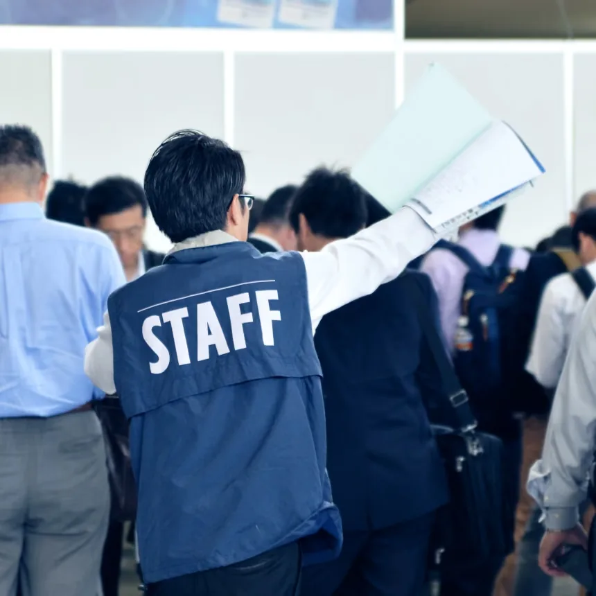 会場でスタッフが来場者を案内している後ろ姿